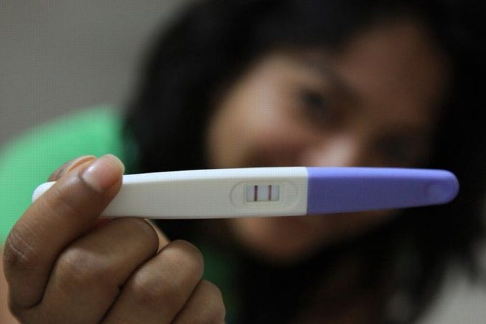 Mujer muestra un positivo en un test de embarazo.